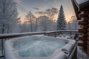Un bain à remous sur une terrasse en bois, avec des arbres enneigés en arrière-plan.