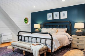 Une chambre à coucher avec un lit, des tables de chevet, un banc et une fenêtre.