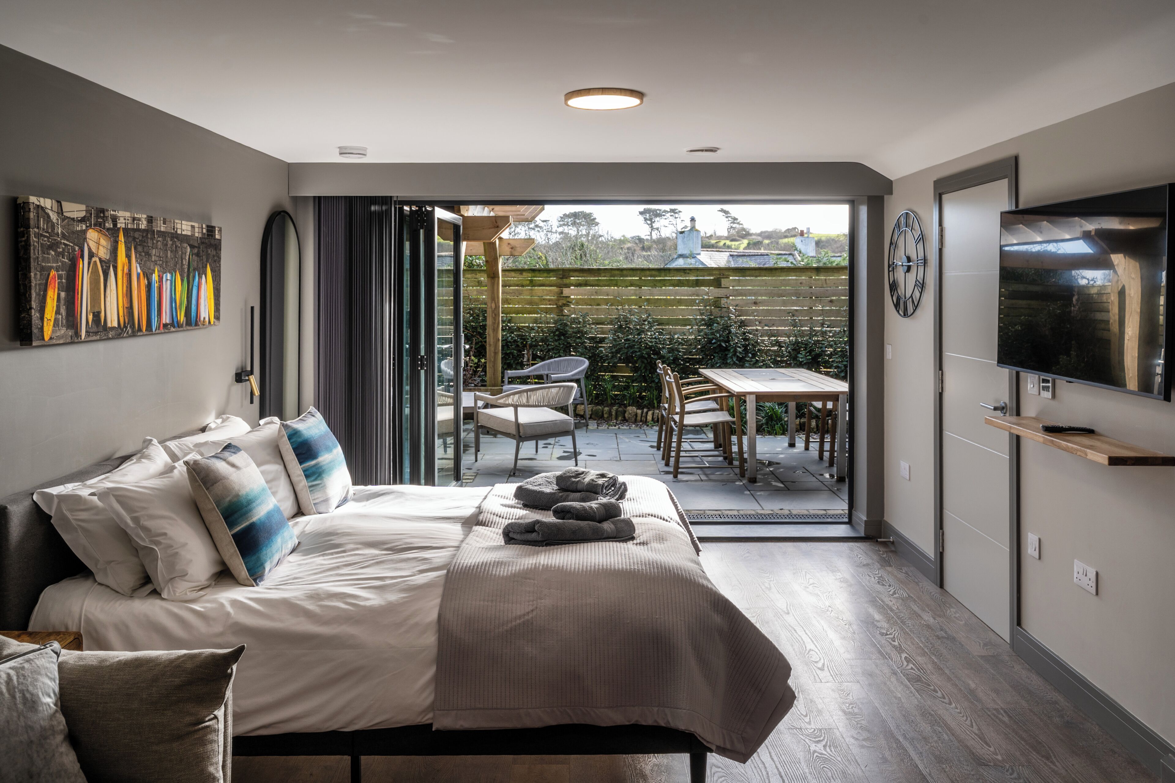 Een slaapkamer met een bed, een televisie, een klok en uitzicht op buiten.