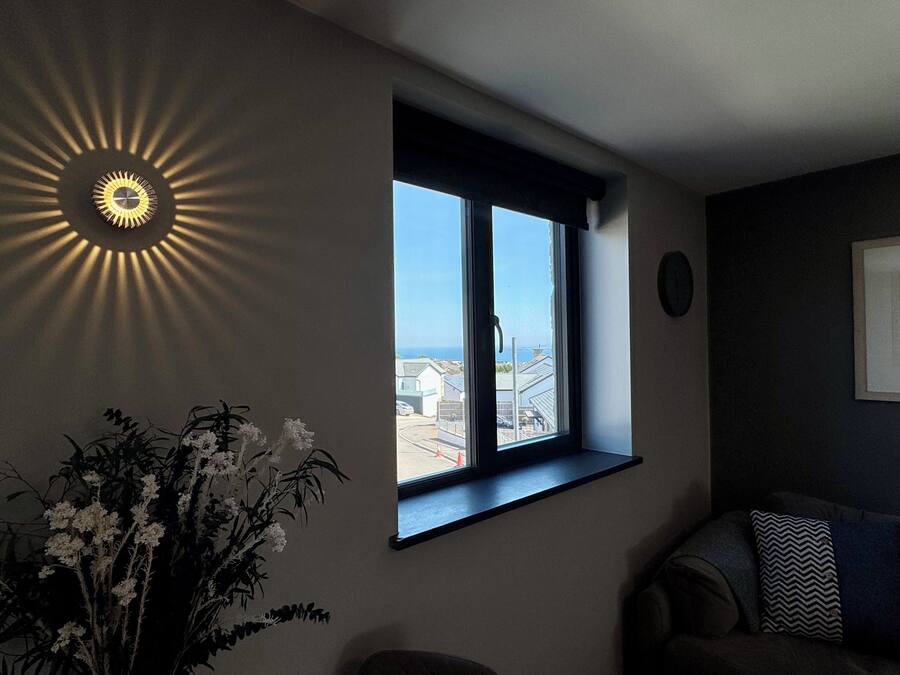 A room with a large window, a wall-mounted light fixture, and a potted plant.