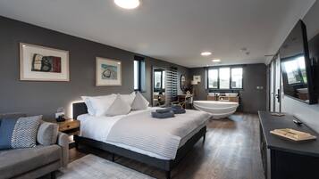 A modern bedroom with a large bed, bedside tables, a sofa, and a built-in bathtub.