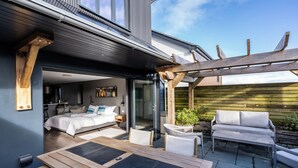 A modern house with a bedroom, a dining area, and a patio with outdoor furniture. - Uno Carbis Bay (St Ives)