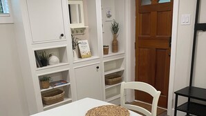 A white dining table with two woven placemats, a patterned rug, and a white chair. -  Gertie's Nook: Charming Private Studio Space close to everything! (Dartmouth)