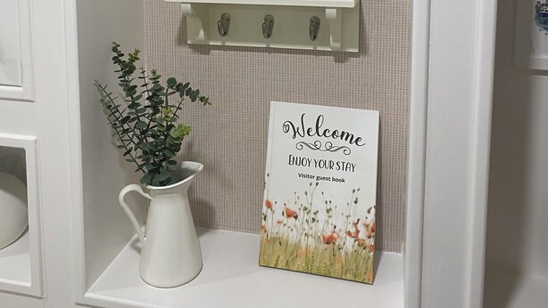 A bathroom with a white sink, a mirror, a small shelf with a welcome sign, and a potted plant. -  Gertie's Nook: Charming Private Studio Space close to everything! (Dartmouth)