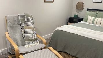 Une chambre à coucher comprenant un lit, une chaise, une table de chevet et une lampe fixée au mur.