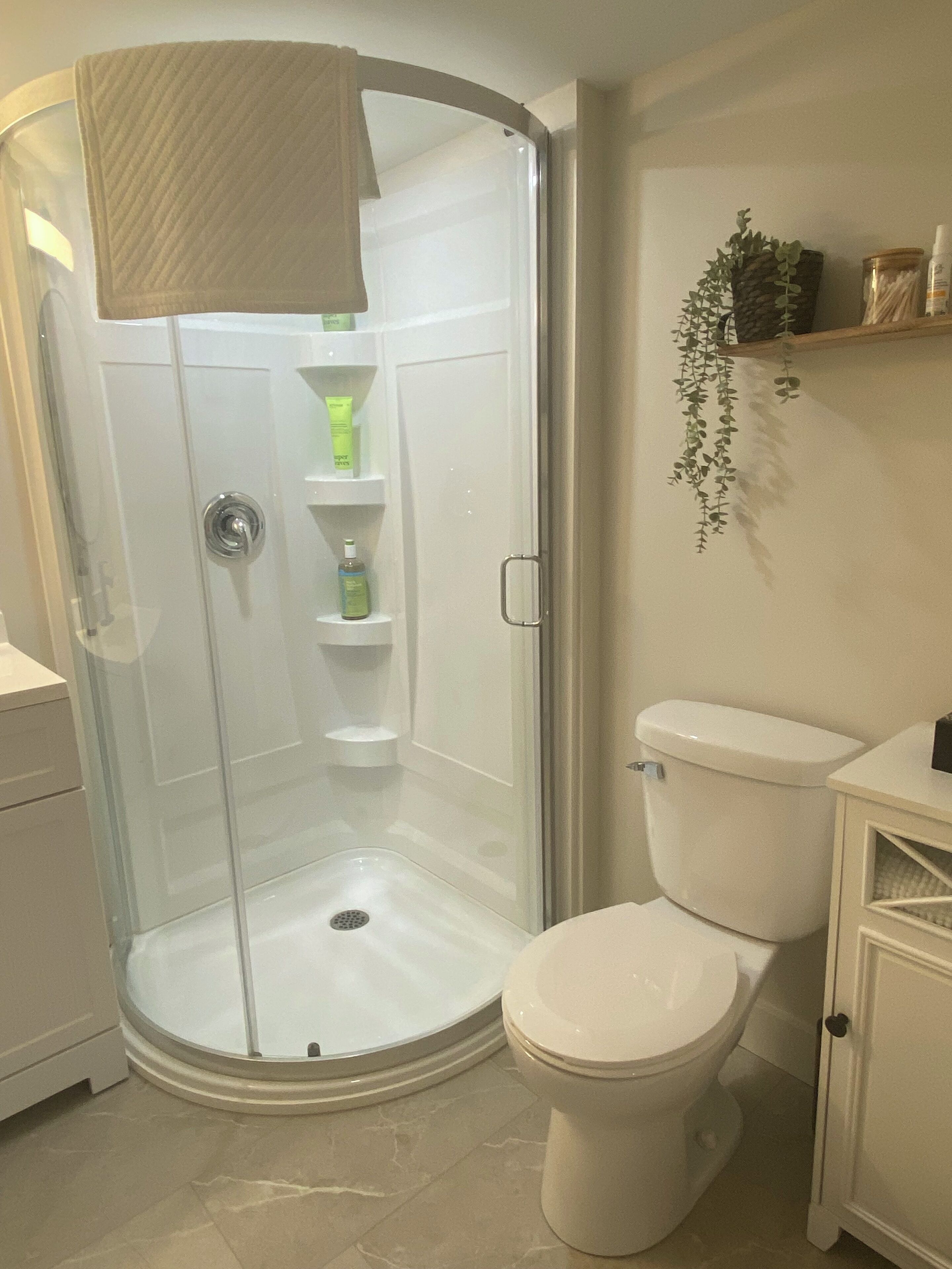 Een badkamer met een douchecabine van glas, een toilet en een plank met toiletartikelen.