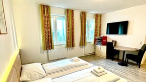 A hotel room with two beds, a desk with a chair, a television, and a radiator. - Apart Hotel Neudörfl (Neudoerfl)