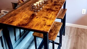 Una mesa de madera para comer con bancos, un candelabro y un enchufe en la pared.