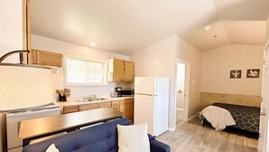 Un espacio habitable compacto con kitchenette, un sofá, una cama y un pequeño comedor.
