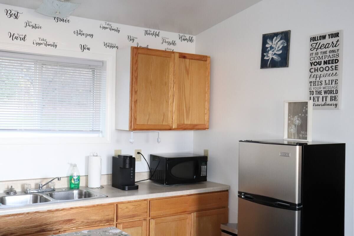A kitchen with wooden cabinets, a stainless steel refrigerator, a microwave, and a coffee maker.