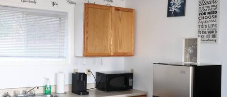 A kitchen with wooden cabinets, a stainless steel refrigerator, a microwave, and a coffee maker.