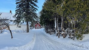 A snow-covered rural road with a red barn and trees on either side. - Spacious 7-bedroom house with WiFi, Garage, Sauna, and AC in amazing Calumet (Calumet)