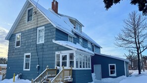 A two-story house with a steep roof, a front porch, and a staircase leading to the entrance. - Spacious 7-bedroom house with WiFi, Garage, Sauna, and AC in amazing Calumet (Calumet)
