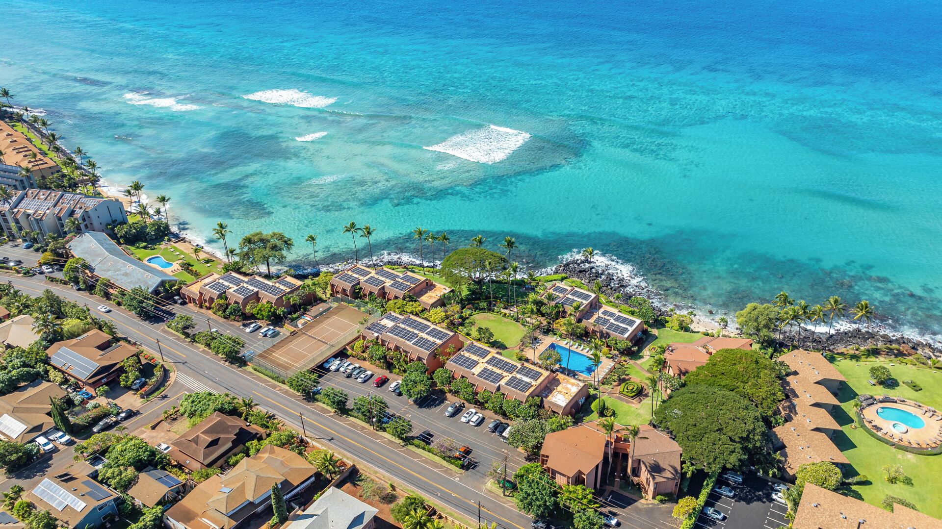 Ein Luftbild eines Küstenresorts mit mehreren Gebäuden, einer Straße und freiem Blick auf den Ozean.