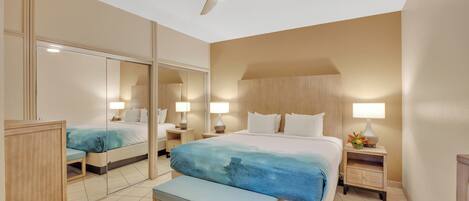 A hotel room with a large bed, a bench, a nightstand, a mirror, and a ceiling fan.