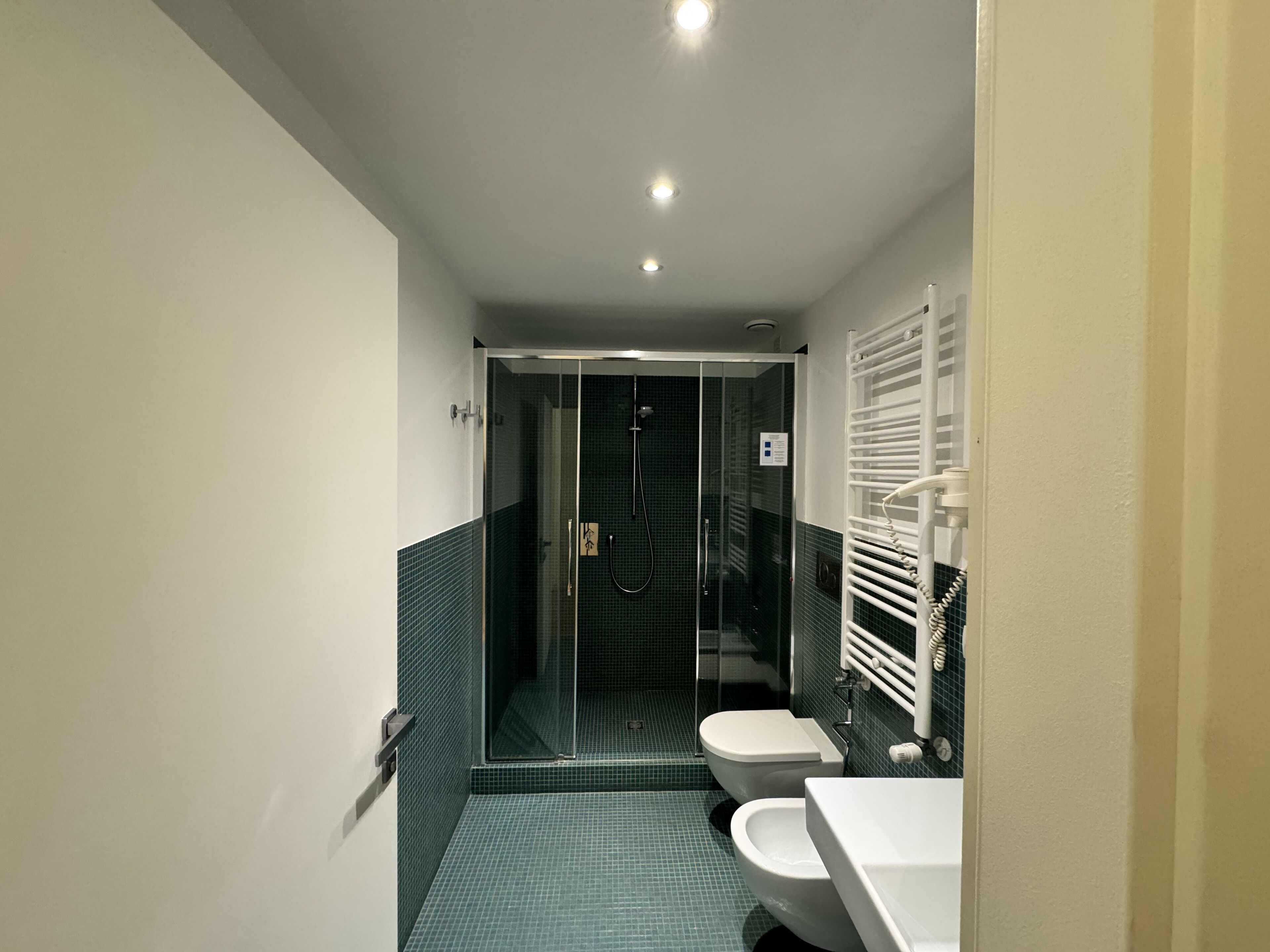 Un baño moderno con ducha de vidrio, lavamanos blanco y retrete.