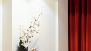 A modern room with a desk, a potted orchid, and a red curtain. - History Suite Essence (Rome)