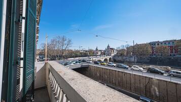 Blick vom Balkon auf eine belebte Straße mit Autos, einer Brücke und Gebäuden im Hintergrund.