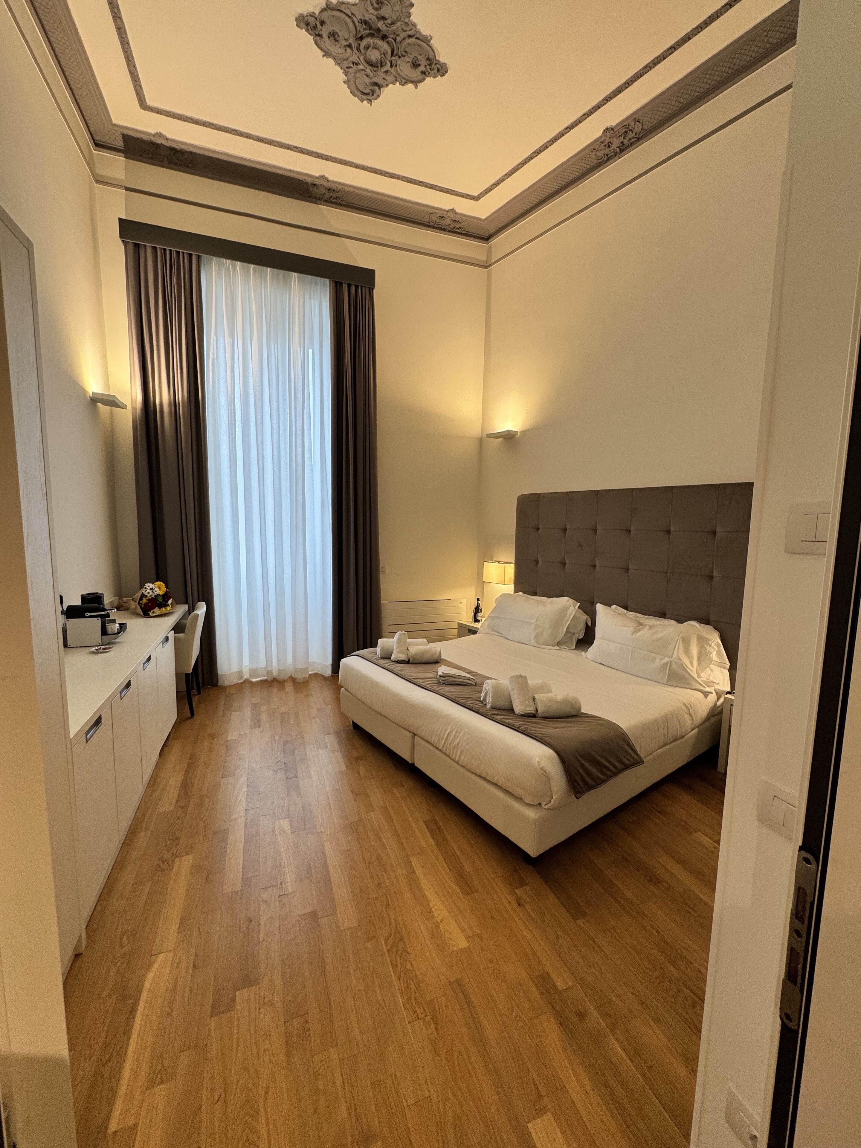 Una habitación de hotel con una cama grande, un escritorio y una ventana con cortinas.