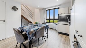 Una cocina moderna con comedor, que incluye una escalera, ventanas amplias y vistas al exterior.