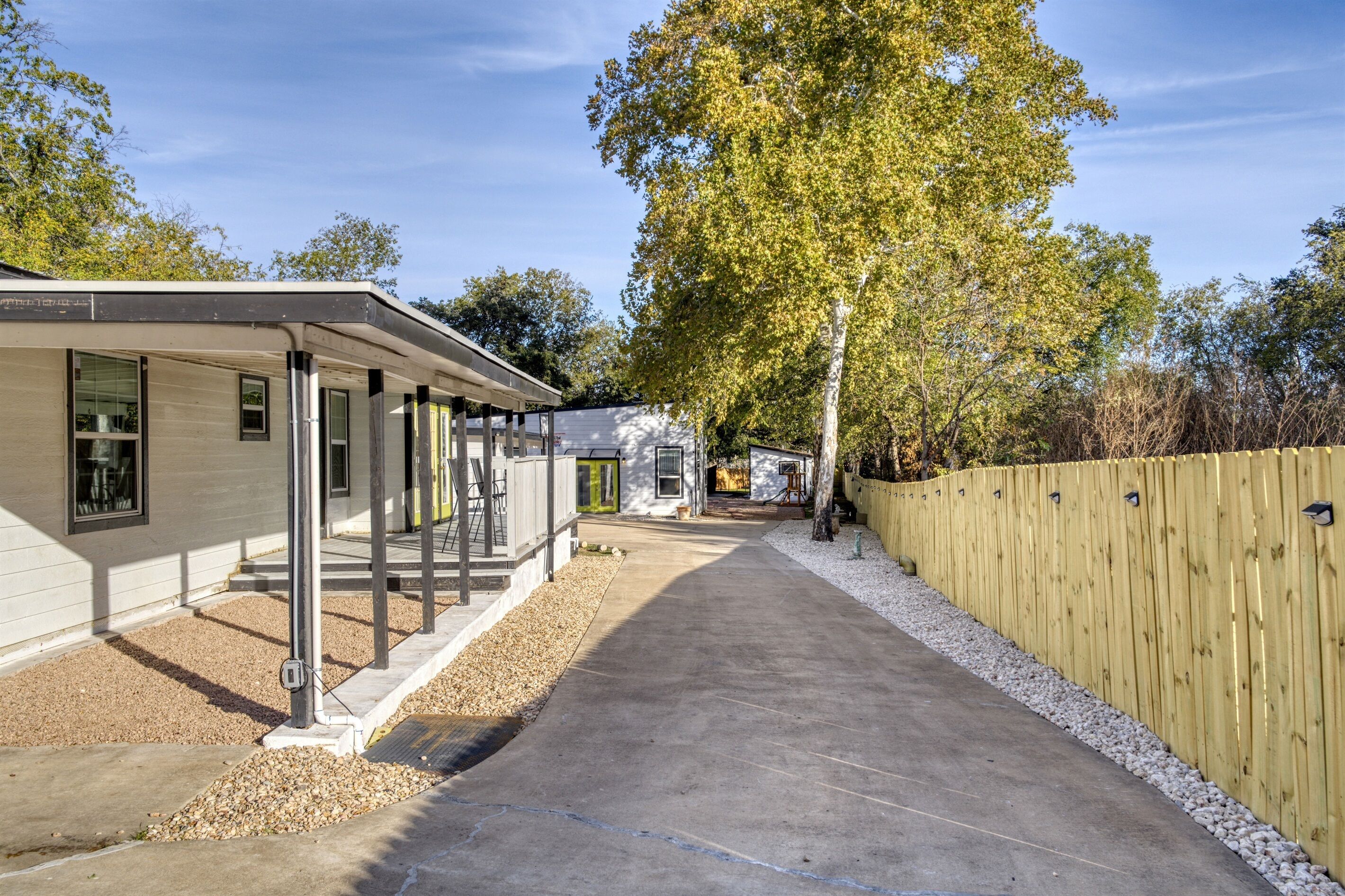 A single-story house with a covered porch, a gravel driveway, and a wooden fence.