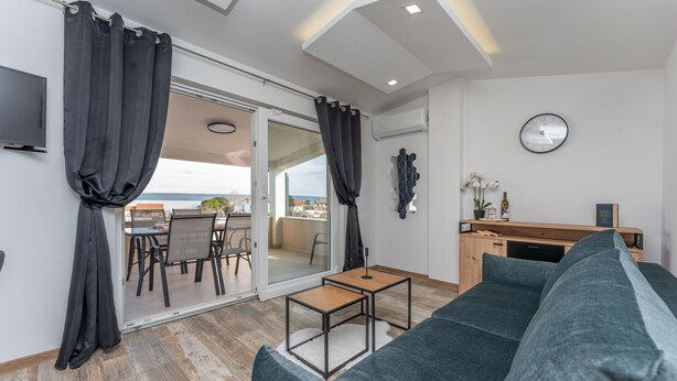A modern living room with a sofa, a small table, and a balcony with a view.
