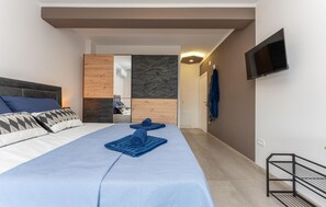A modern bedroom with a bed, a TV, and a wooden panel wall. - Stunning home in Banj (Banj)