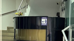 A reception area with a black counter, a hand sanitizer dispenser, and a staircase with metal railings. - hotel golden star (Batumi)