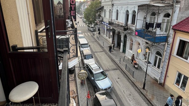 A hotel with a balcony, a street view, and parked cars. - hotel golden star (Batumi)