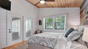 Un dormitorio con cama, ventilador de techo, ventana y puerta con persianas.