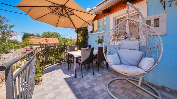 Eine Terrasse mit einer Hängematte, einem Tisch mit Stühlen und einem großen Sonnenschirm.