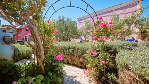 Ein Garten mit einem Kiesweg, rosa Blumen und einem roten Vogelhaus.