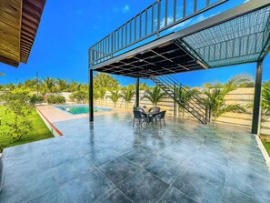 A covered outdoor area with a pool, seating, and a staircase leading to an upper level. - Relax, Refresh & Recharge (Kanakamamidi)