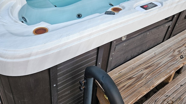 Un jacuzzi con panel de control digital, integrado en una estructura de madera.