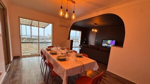 A dining area with a table set for four, a TV in the background, and a view through the window. - 3-bedroom 110m² apartment with terrace, view (Thiers)