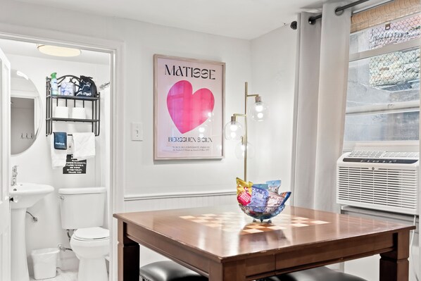 A modern bathroom with a toilet, sink, and a shower area. There is a framed artwork on the wall and a table with a bowl of snacks. - Cozy 1 Bed, 1 Bath - Near Downtown and U of U. (Salt Lake City)