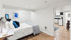 A bedroom with a bed, bedside table, and a nightstand. There is a door leading to a kitchen area. - Cozy 1 Bed, 1 Bath - Near Downtown and U of U. (Salt Lake City)