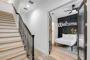 Un dormitorio con una cama, un cartel que dice 'Welcome', un ventilador de techo y una escalera.