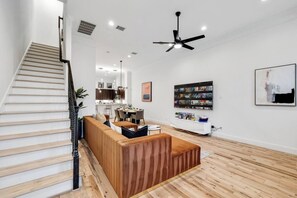 A modern interior with a staircase, a dining area, a seating area, and a wall-mounted TV.
