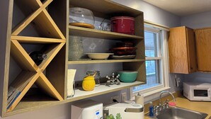 A kitchen with wooden shelves, a microwave, a sink, and various kitchenware. - Relax at Skylark's Nest (McGaheysville)