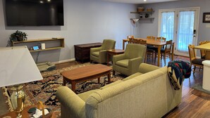 A living room with a sofa, armchairs, a coffee table, a TV, and a dining area with a table and chairs. - Relax at Skylark's Nest (McGaheysville)