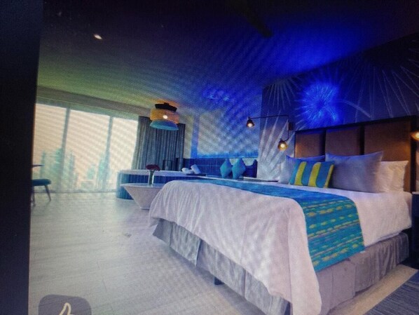 Relax in a spacious room with a large bed, wall-mounted TV, and a small table with a chair.