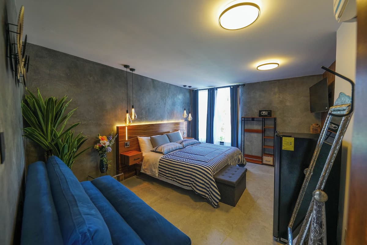 Une chambre moderne avec un grand lit, un banc, un bureau et une armoire.
