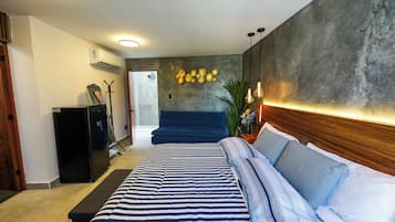 Un dormitorio moderno con una cama grande, un cabecero azul oscuro y un aire acondicionado instalado en la pared.