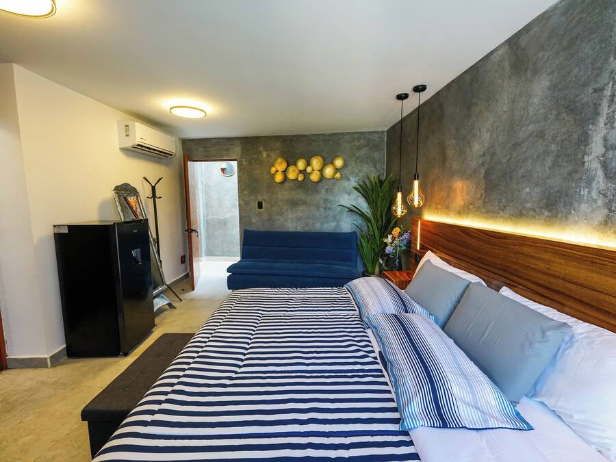 Un dormitorio moderno con una cama grande, un cabecero azul oscuro y un aire acondicionado instalado en la pared.