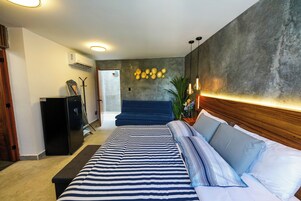 Un dormitorio moderno con una cama grande, un cabecero azul oscuro y un aire acondicionado instalado en la pared.