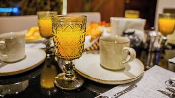 A breakfast setting with a table set for two, including plates, cups, and a glass with a yellow beverage.