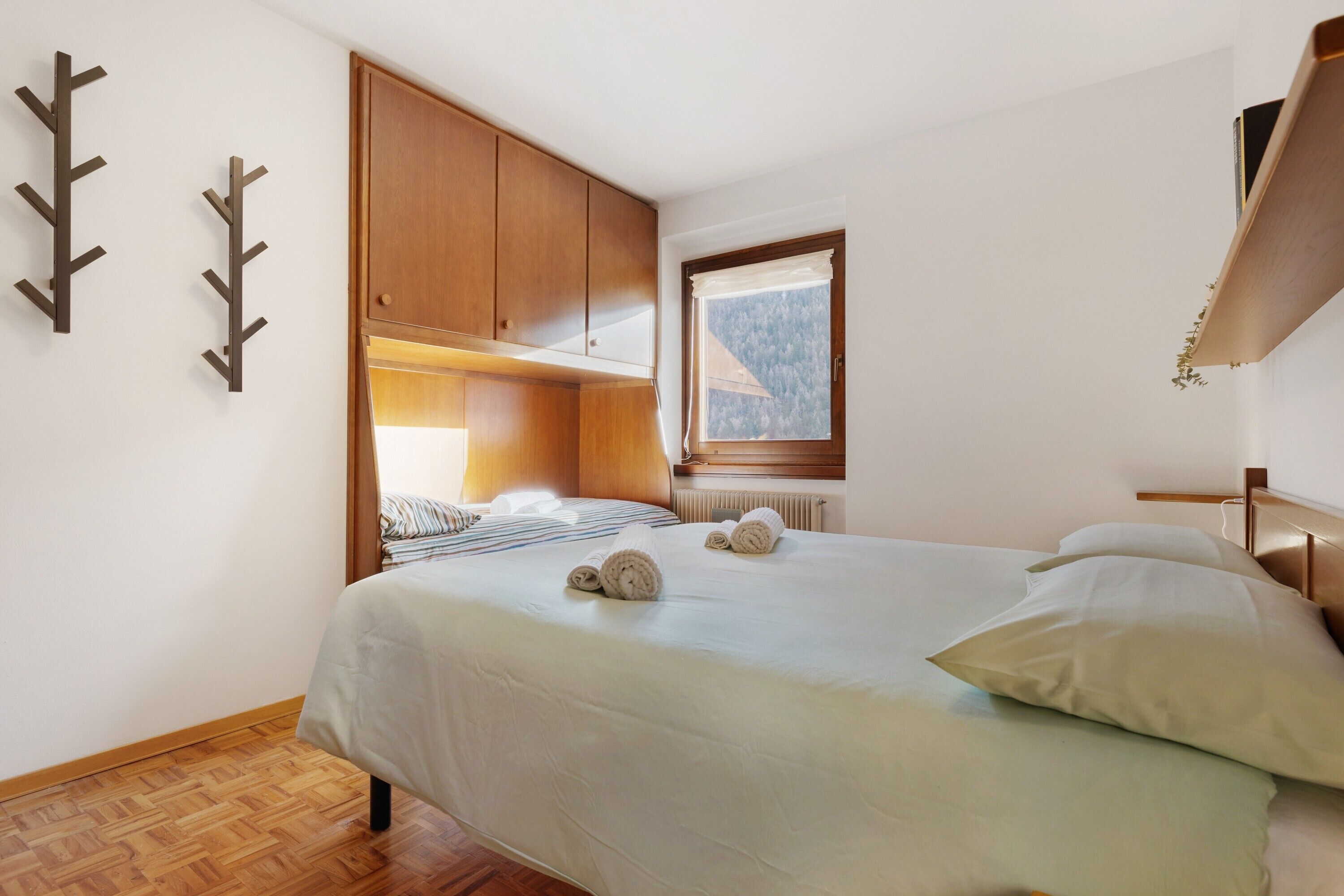 Ein Schlafzimmer mit Bett, Holzschrank und Fenster mit Blick.