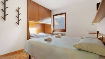 Ein Schlafzimmer mit Bett, Holzschrank und Fenster mit Blick.