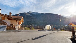 A mountain view with a road, a small white building, and a wooden house.